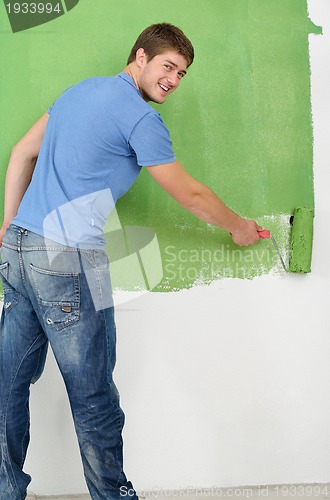 Image of handsome young man paint white wall in color