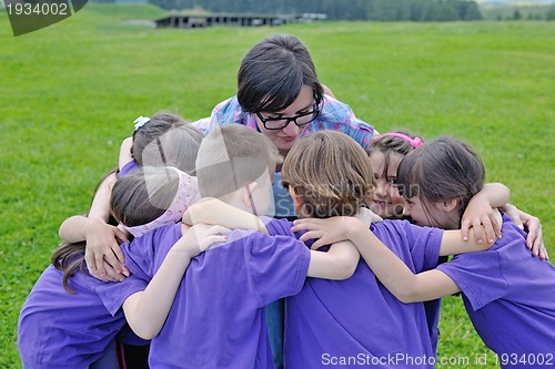 Image of happy kids group with teacher in nature