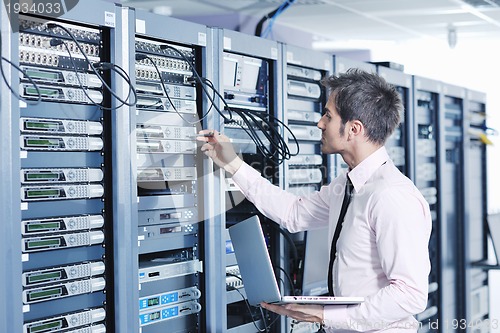 Image of businessman with laptop in network server room