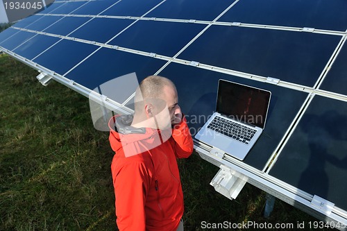 Image of engineer using laptop at solar panels plant field