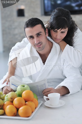 Image of Happy couple reading the newspaper in the kitchen at breakfast