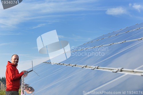 Image of engineer using laptop at solar panels plant field