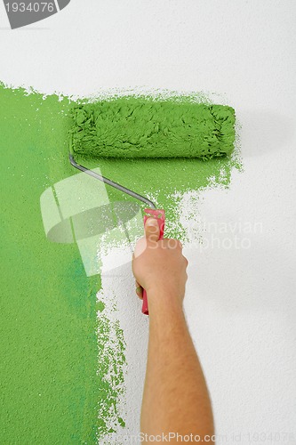 Image of handsome young man paint white wall in color