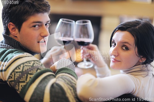 Image of Young romantic couple sitting and relaxing in front of fireplace