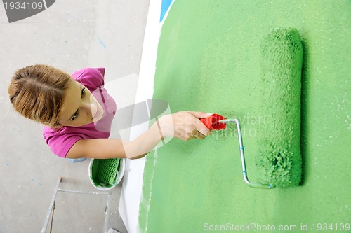 Image of happy smiling woman painting interior of house