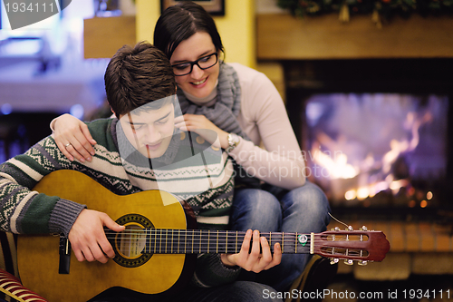 Image of Young romantic couple sitting on sofa in front of fireplace at h