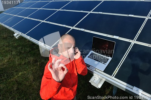 Image of engineer using laptop at solar panels plant field