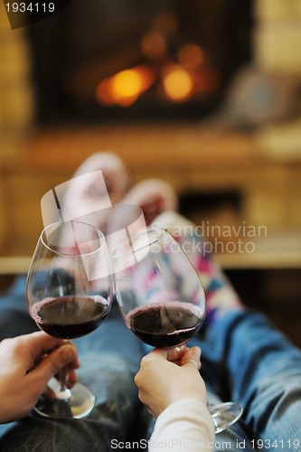 Image of Young romantic couple sitting and relaxing in front of fireplace
