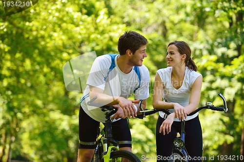 Image of Happy couple riding bicycle outdoors