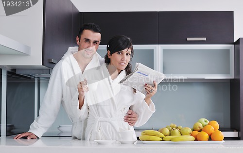 Image of Happy couple reading the newspaper in the kitchen at breakfast