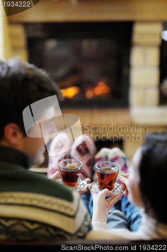 Image of Young romantic couple relax on sofa in front of fireplace at hom