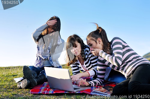 Image of group of teens working on laptop outdoor