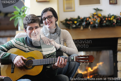 Image of Young romantic couple sitting on sofa in front of fireplace at h