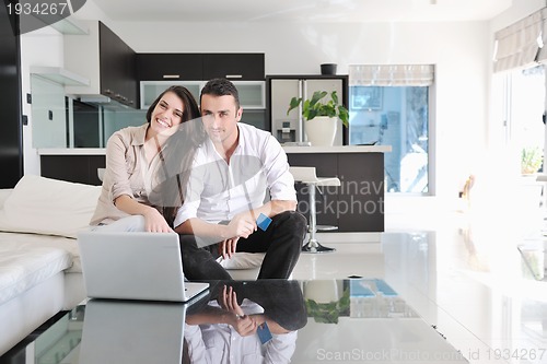 Image of joyful couple relax and work on laptop computer at modern home