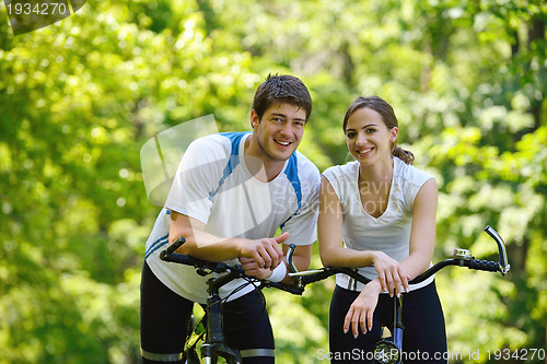 Image of Happy couple riding bicycle outdoors