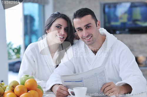 Image of Happy couple reading the newspaper in the kitchen at breakfast