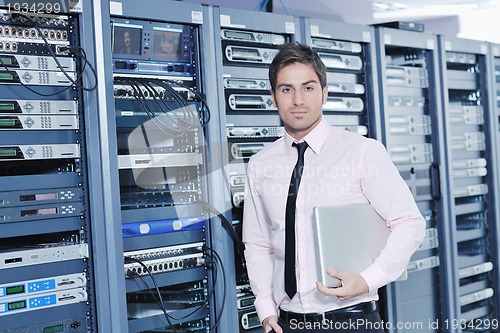 Image of businessman with laptop in network server room