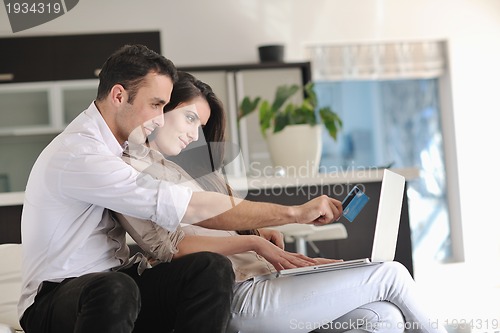 Image of joyful couple relax and work on laptop computer at modern home