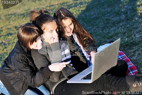 Image of group of teens working on laptop outdoor