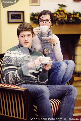 Image of Young romantic couple sitting and relaxing in front of fireplace