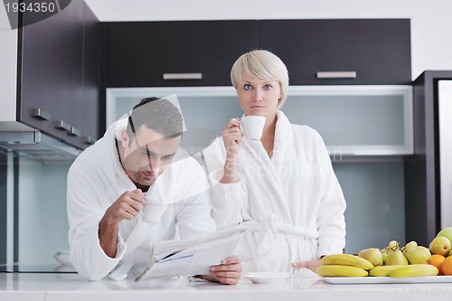 Image of Happy couple reading the newspaper in the kitchen at breakfast
