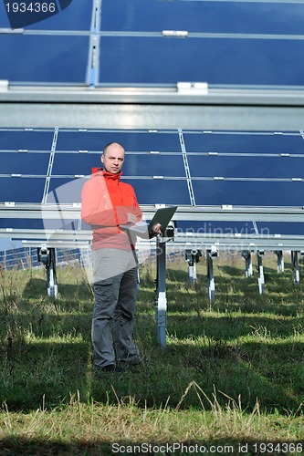 Image of engineer using laptop at solar panels plant field