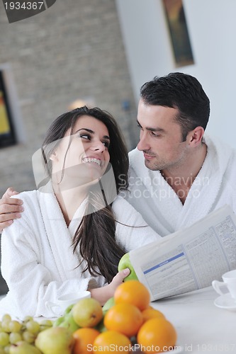 Image of Happy couple reading the newspaper in the kitchen at breakfast