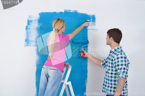 Image of happy couple paint wall at new home