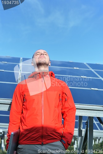 Image of engineer using laptop at solar panels plant field