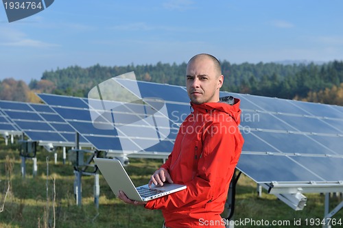 Image of engineer using laptop at solar panels plant field