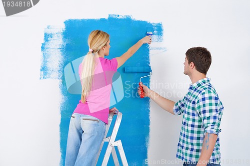 Image of happy couple paint wall at new home