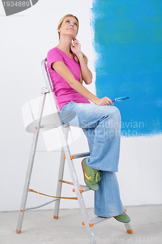 Image of happy smiling woman painting interior of house