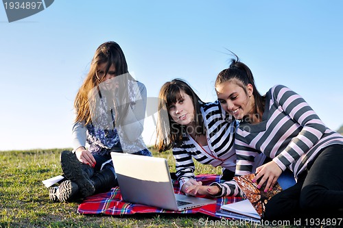 Image of group of teens working on laptop outdoor