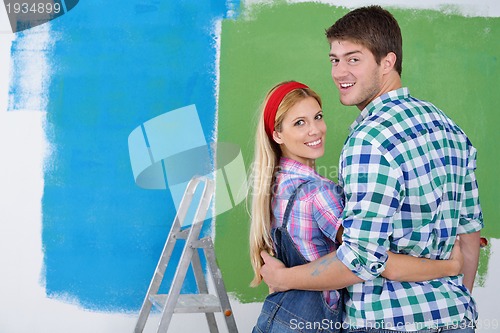 Image of happy couple paint wall at new home