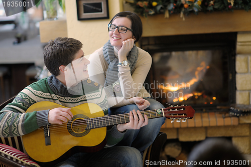 Image of Young romantic couple sitting on sofa in front of fireplace at h