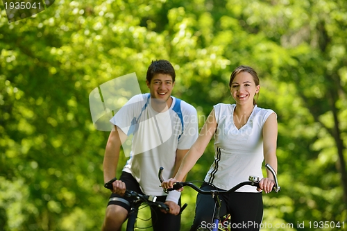 Image of Happy couple riding bicycle outdoors