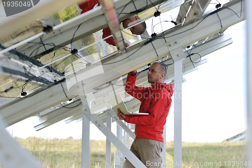 Image of engineer using laptop at solar panels plant field