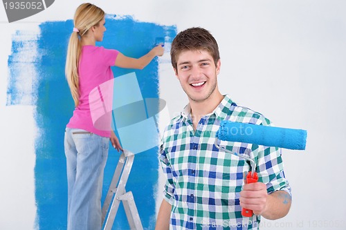 Image of happy couple paint wall at new home