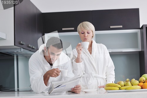 Image of Happy couple reading the newspaper in the kitchen at breakfast