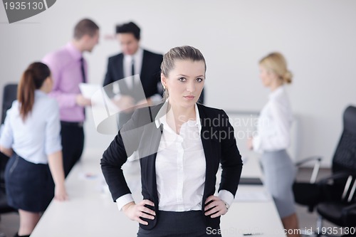 Image of business woman standing with her staff in background