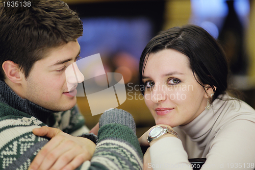 Image of Young romantic couple relax on sofa in front of fireplace at hom