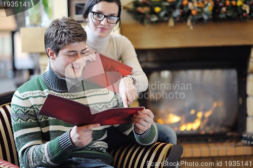 Image of Young romantic couple sitting and relaxing in front of fireplace