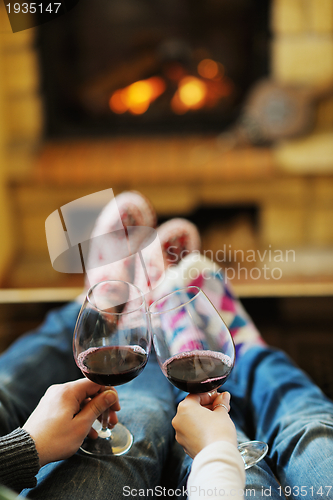 Image of Young romantic couple sitting on sofa in front of fireplace at h