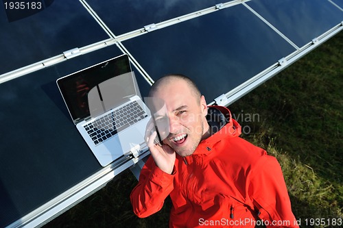 Image of engineer using laptop at solar panels plant field