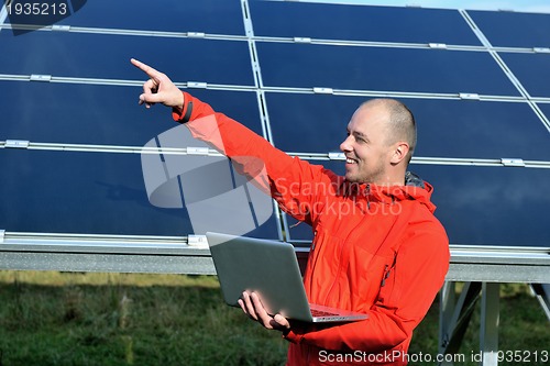 Image of engineer using laptop at solar panels plant field