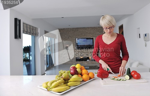 Image of happy  beautiful blonde  woman prepare food in  the kitchen