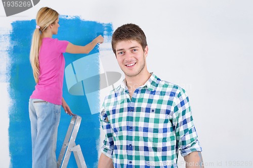 Image of happy couple paint wall at new home