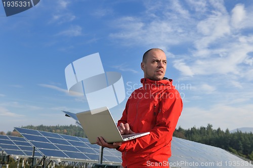 Image of engineer using laptop at solar panels plant field