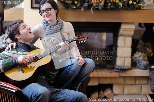 Image of Young romantic couple relax on sofa in front of fireplace at hom