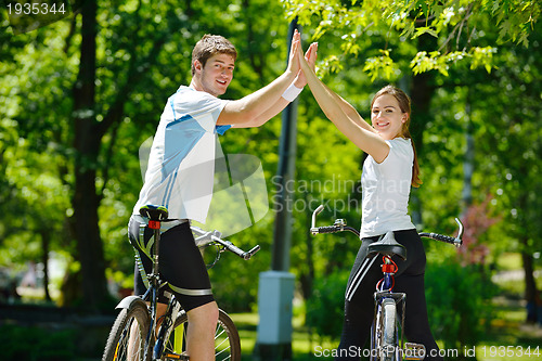 Image of Happy couple riding bicycle outdoors